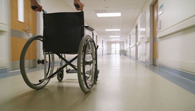 Healthcare worker pushing wheelchair down hospital corridor patient transport concept