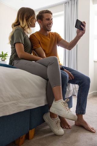 Happy Couple Taking Selfie in Cozy Bedroom Environment