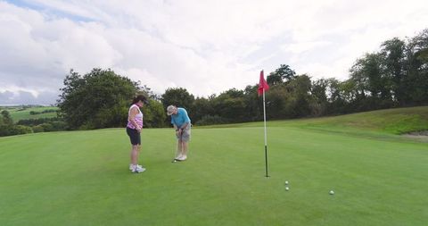 Senior Couple Putting on Lush Golf Course Green