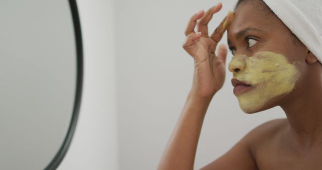Happy african american woman apply beauty mask on face in bathroom - Download Free Stock Photos Pikwizard.com