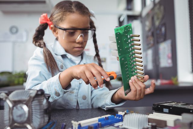 Young girl concentrating while assembling a circuit board in an electronics lab. Ideal for use in educational materials, STEM programs, technology and engineering promotions, and content focused on children's learning and creativity.