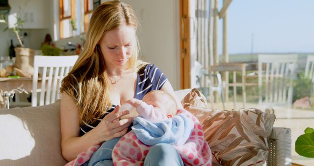 Mother Feeding Infant with Baby Bottle in Sunlit Living Room - Download Free Stock Images Pikwizard.com