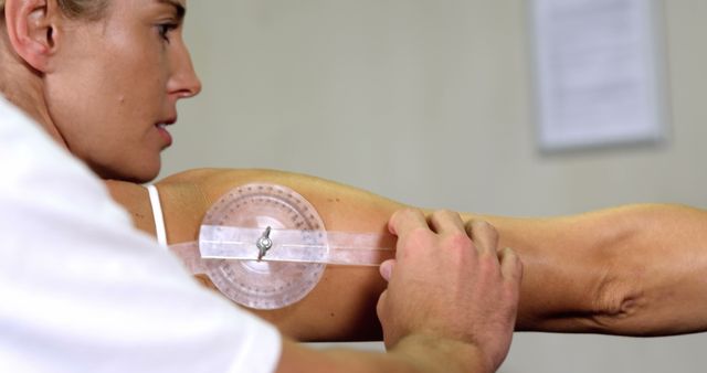 Focuses on a physiotherapist measuring a patient's arm using a goniometer, emphasizing the practice of physical therapy and muscle assessment. Suitable for content related to healthcare, therapy best practices, and fitness training.