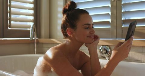 Relaxed Woman Watching Smartphone During Bath Time