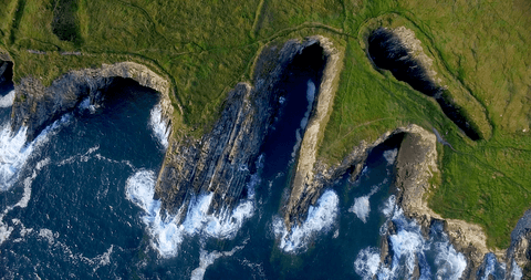 transparent waves crash against rugged green cliff coastline - Download Free Stock Videos Pikwizard.com