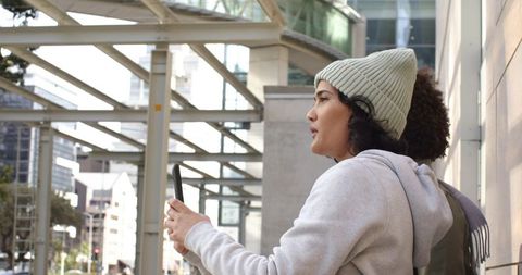 Multicultural women exploring city and navigating with smartphone under glass canopy