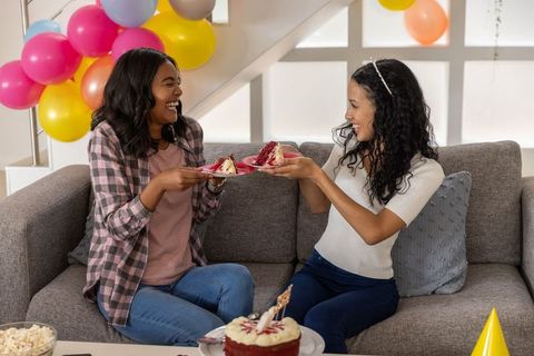 Joyful friends celebrating birthday with cake and balloons at home