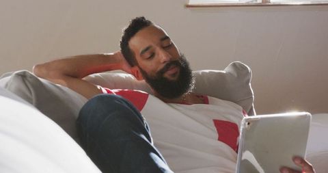Man Relaxing on Sofa Using Tablet
