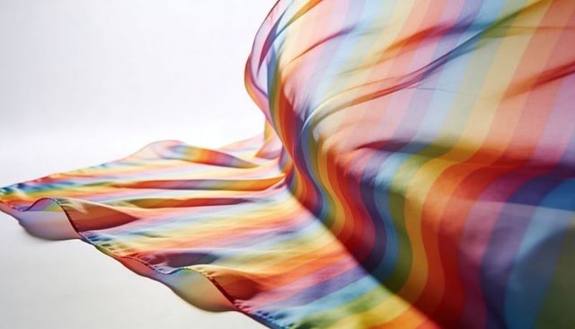 Flowing rainbow-striped satin fabric forming curving folds and glossy sheen, lustrous