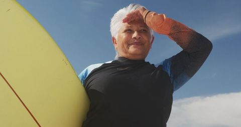 Active Senior Woman Holding Surfboard on Sunny Beach
