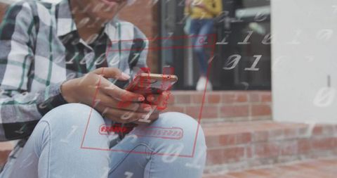 Teen holding smartphone tapping on brick steps with red digital overlay