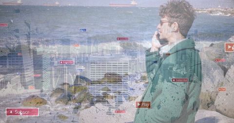 Man by rocky seashore engaged in mobile technology interaction