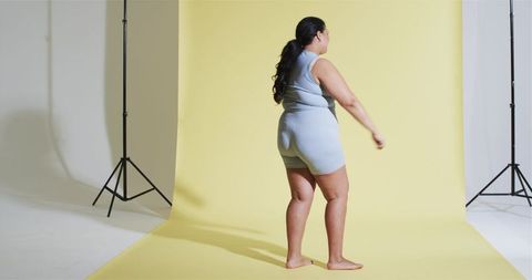 Confident woman in blue activewear on yellow backdrop