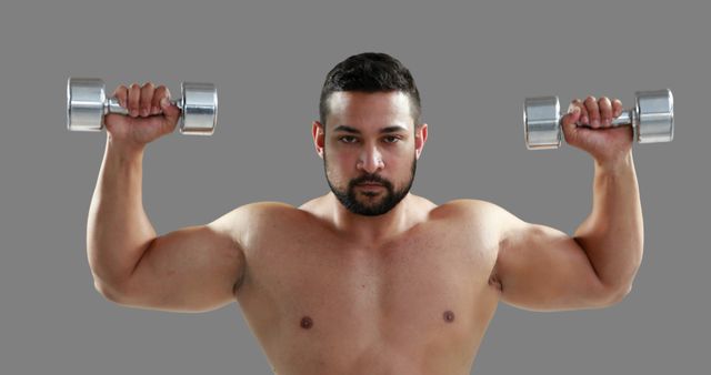 A muscular young Caucasian man is lifting dumbbells in a fitness setting, with copy space - Download Free Stock Photos Pikwizard.com