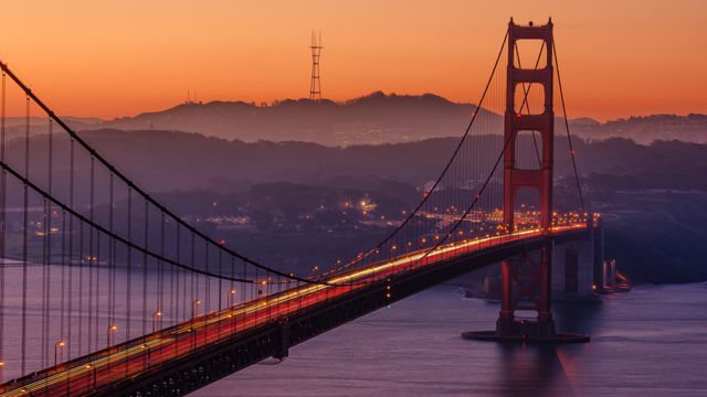 Depicts Golden Gate Bridge at twilight with San Francisco hills in background. Suitable for articles about travel, landmarks, urban exploration, tourism, and San Francisco.