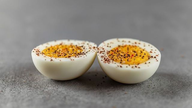 Gourmet hard-boiled egg halves with seasonings on gray countertop