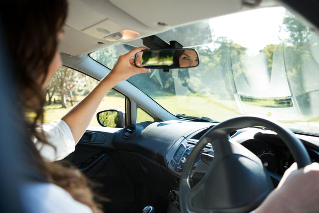 Woman looking into rear view mirror while driving a car - Download Free Stock Photos Pikwizard.com