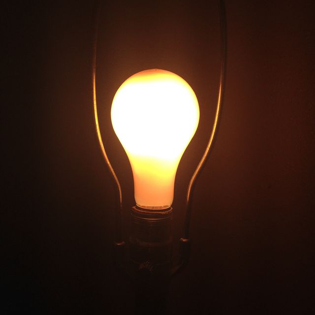 Close-up of a glowing light bulb against a dark background. It evokes a sense of warmth, energy, and simplicity. Suitable for concepts related to energy, innovation, ideas, home decor, and electrical components.