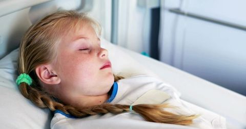 Young girl sleeping in hospital bed, resting during pediatric recovery and care