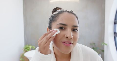 Young woman practicing daily skincare in modern bathroom