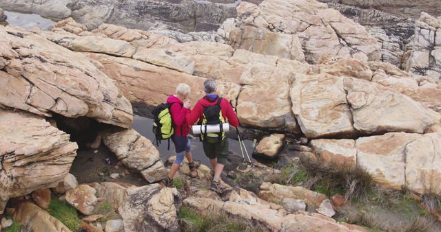 Senior couple spending time in nature, walking on rocks carrying backpacks, holding hands in slow motion. healthy lifestyle fitness retirement.