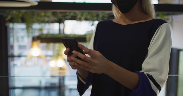 Person Wearing Black Face Mask using Smartphone Indoors - Download Free Stock Images Pikwizard.com