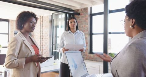 Diverse women collaborating on business financial plans in modern office