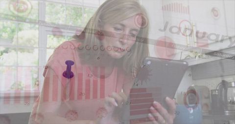 Mature woman analyzing digital data with tablet in kitchen