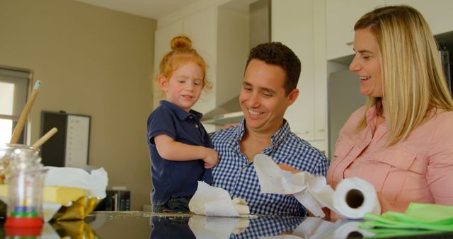 Parents teaching their son to clean kitchen worktop. Mother throwing tissue paper on worktop 4k