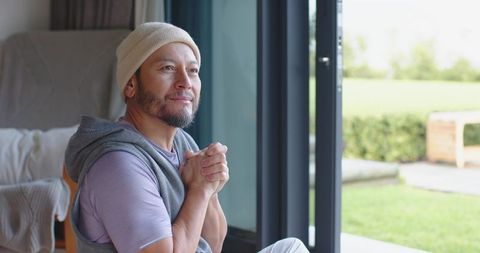 Contemplative mature man reflecting indoors with outdoor view