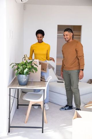 Diverse Couple Unpacking Boxes in Modern Living Room