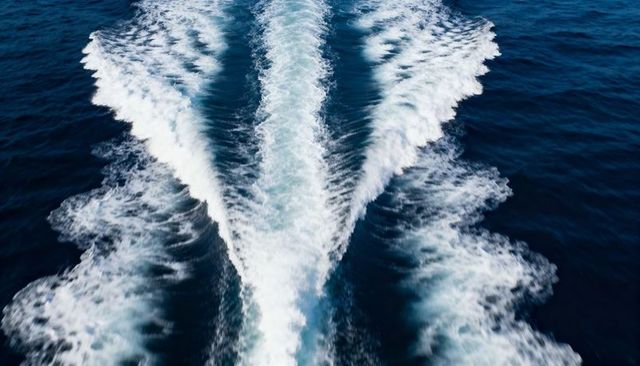 V-shaped boat wake cutting through deep blue ocean foam trail showing motion and power