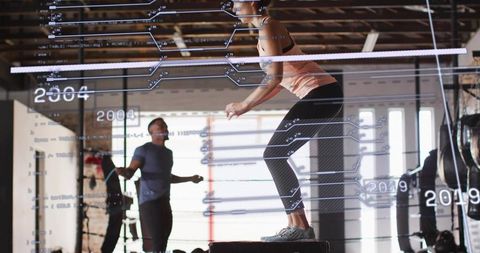Female Athlete Doing Box Jump While Training Partner Skipping Rope with Digital Data Overlays