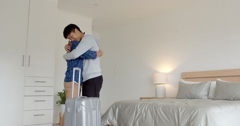 Two men hugging before journey in modern bedroom