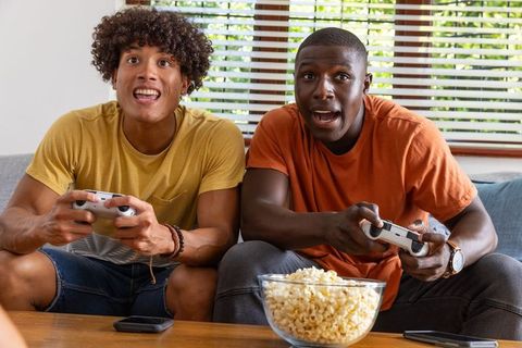 Friends Enthusiastically Gaming with Snacks and Consoles