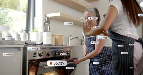 Daughter guiding senior woman opening oven with ar labels in bright modern home kitchen