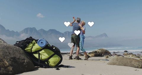 Happy Couple Dancing on Scenic Beach with Hiking Gear