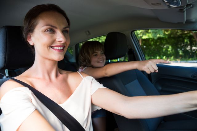 Happy woman driving a car while daughter sitting in the backseat of car