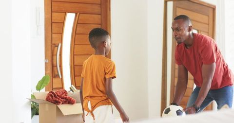 Father teaching son soccer passing in foyer during moving day bonding and coaching moment