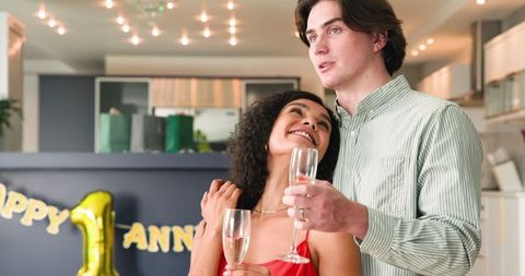 Happy Multiracial Couple Celebrating With Champagne at Anniversary Party