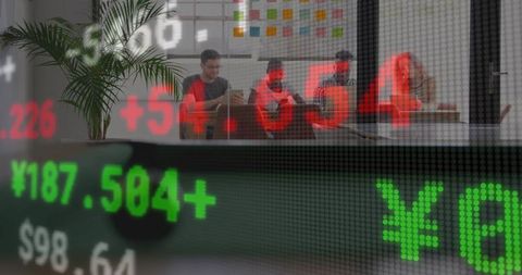 Team reviewing market data with stock ticker overlay in casual office collaboration