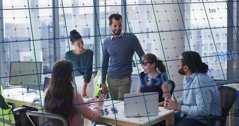 Diverse Team Collaborating in Office with Laptops and Charts