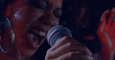 Female Vocalist Singing into Microphone on Club Stage with Neon Star Projections