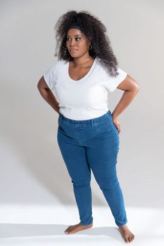 Confident plus-size mid-adult african american woman posing barefoot in jeans and white tee