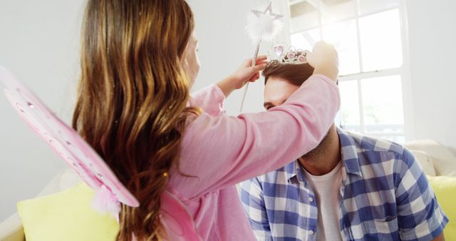 Girl dressed up in a fairy costume placing tiara on fathers head at home 4k