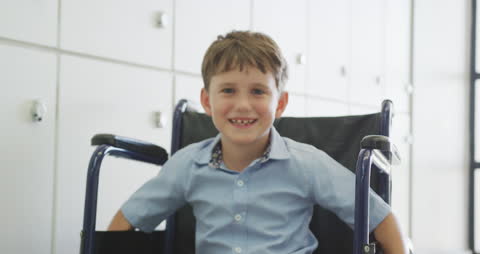 Happy Boy in Wheelchair Smiling in School Hallway