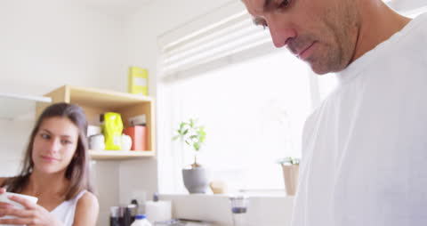 Couple Interacting on Mobile Device in Bright Domestic Kitchen