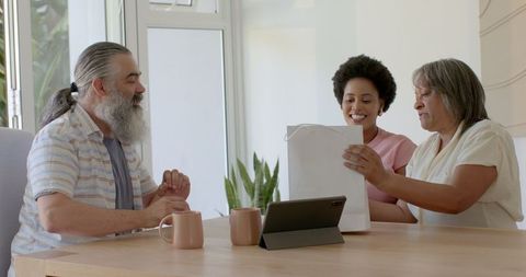 Senior Couple Receiving Gift Bag from Family Member at Table