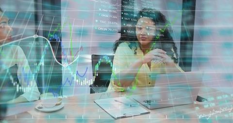 Lead woman reviewing market data on laptop with finance charts overlay in boardroom