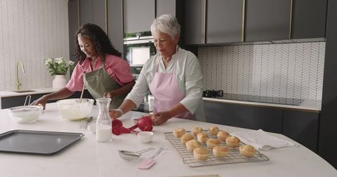 Multigenerational duo baking together in modern kitchen with freshly baked muffins
